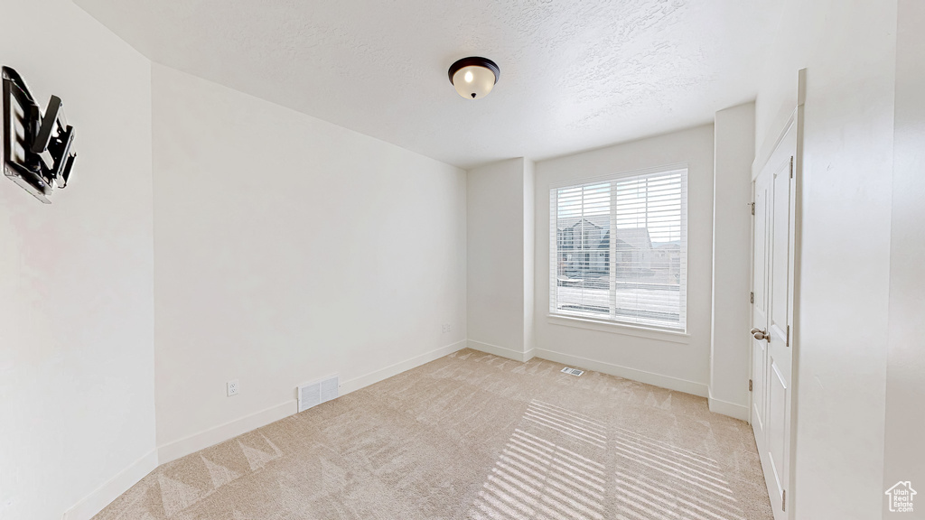 Carpeted spare room with a textured ceiling and baseboards