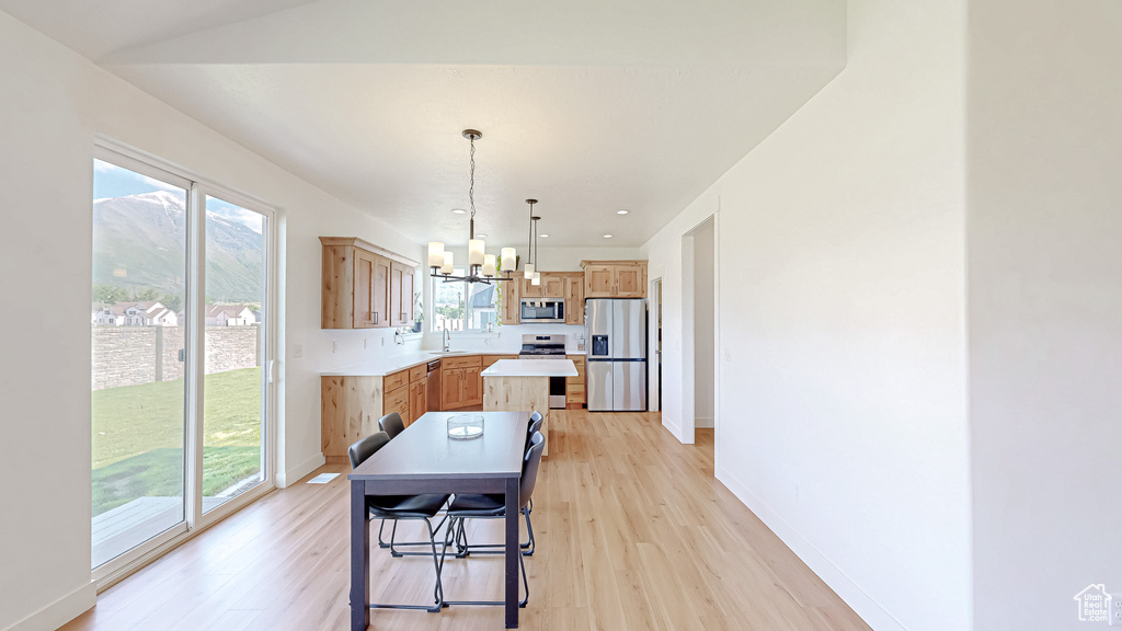 Dining space featuring a chandelier, plenty of natural light, light wood finished floors, and baseboards