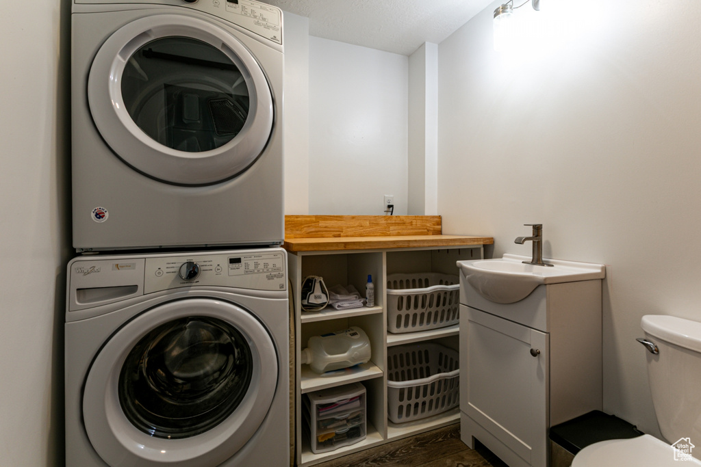 Laundry area with stacked washer and clothes dryer and dark wood finished floors