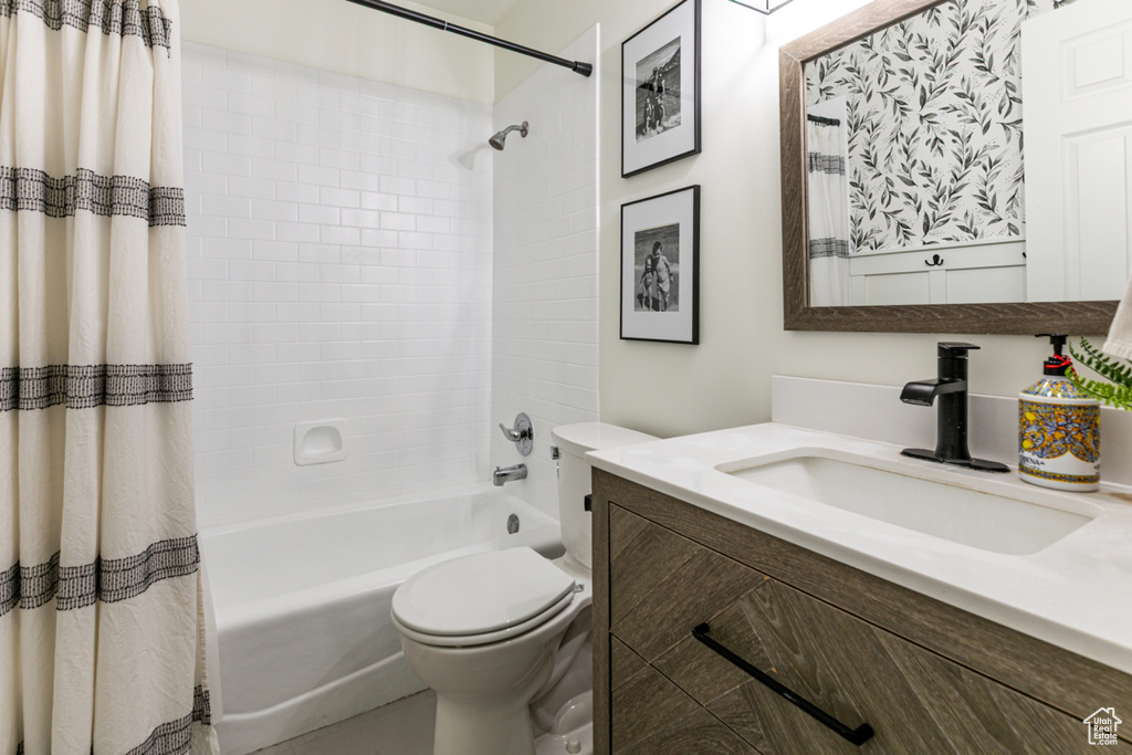 Bathroom featuring vanity, shower / bath combo, and toilet