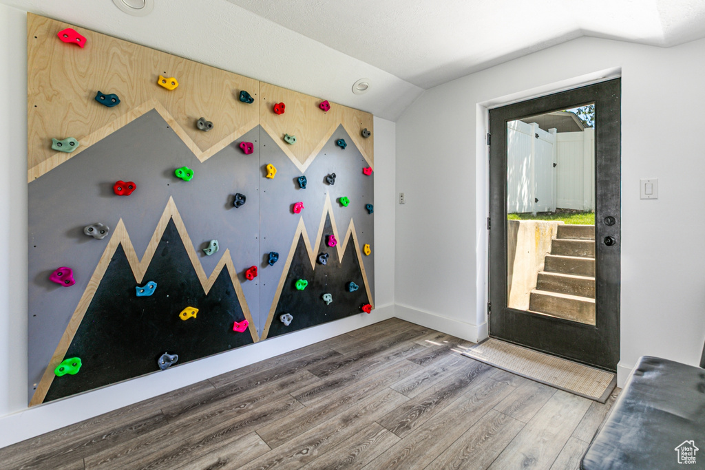 Rec room featuring wood finished floors, vaulted ceiling, and baseboards