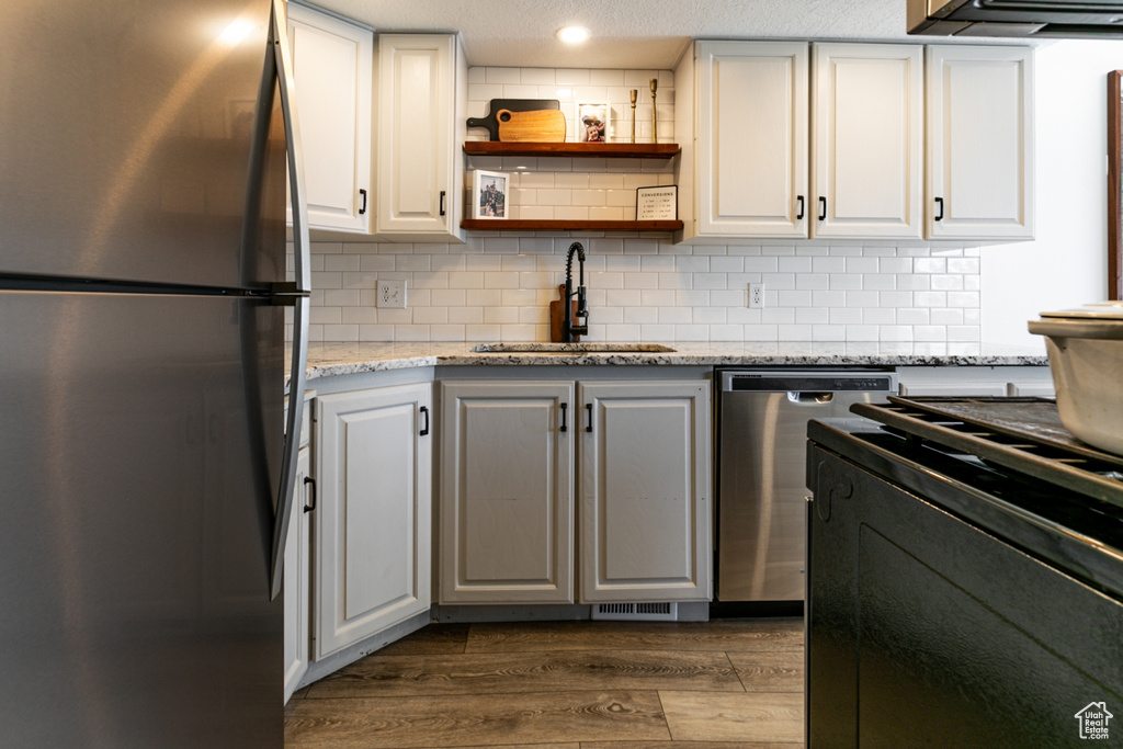 Kitchen featuring stainless steel appliances, a sink, dark wood-style floors, and decorative backsplash