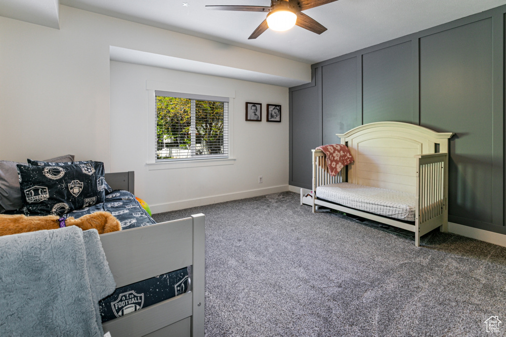 Carpeted living room featuring a ceiling fan and baseboards