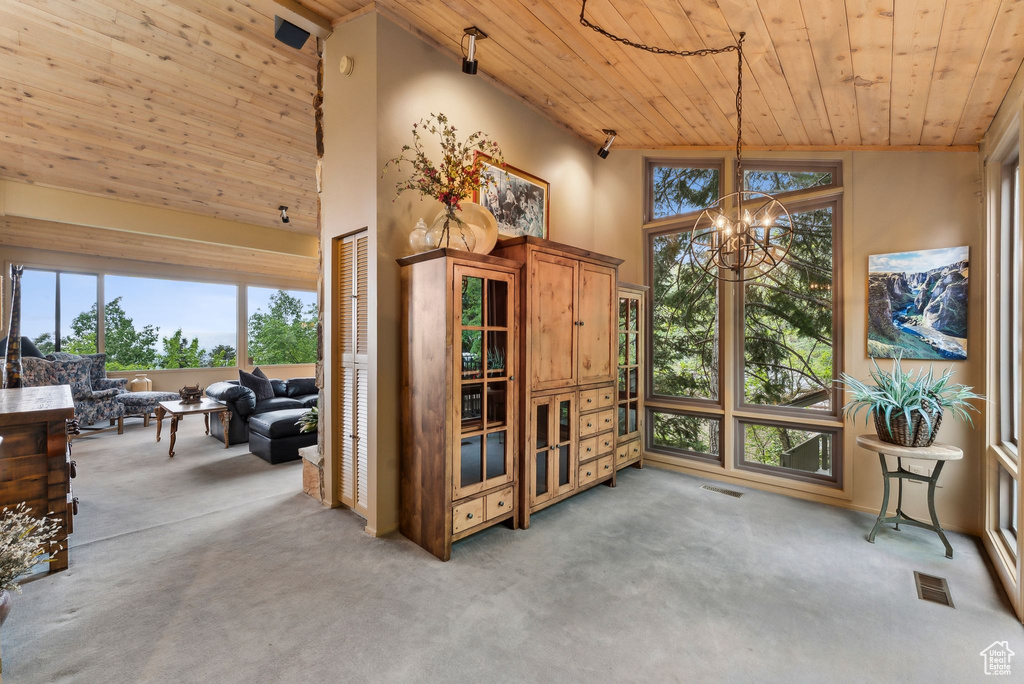 Interior space with wooden ceiling, light carpet, a chandelier, a towering ceiling, and plenty of natural light