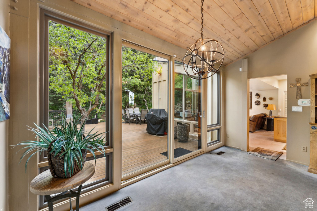 Doorway to outside with a chandelier, wood ceiling, carpet flooring, and vaulted ceiling