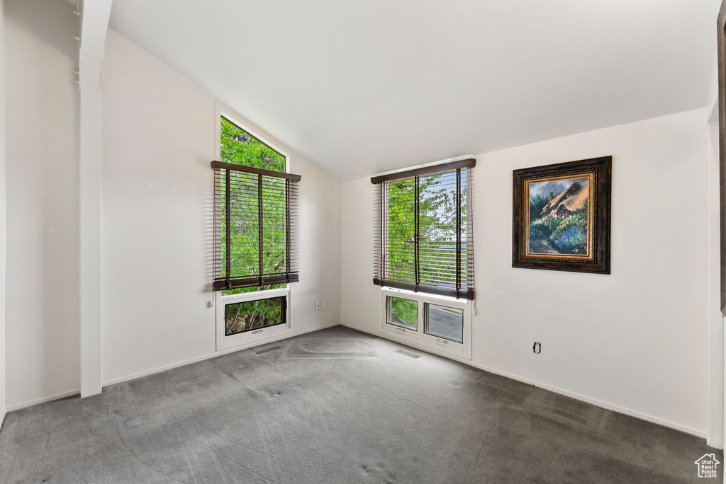Carpeted spare room with vaulted ceiling and baseboards