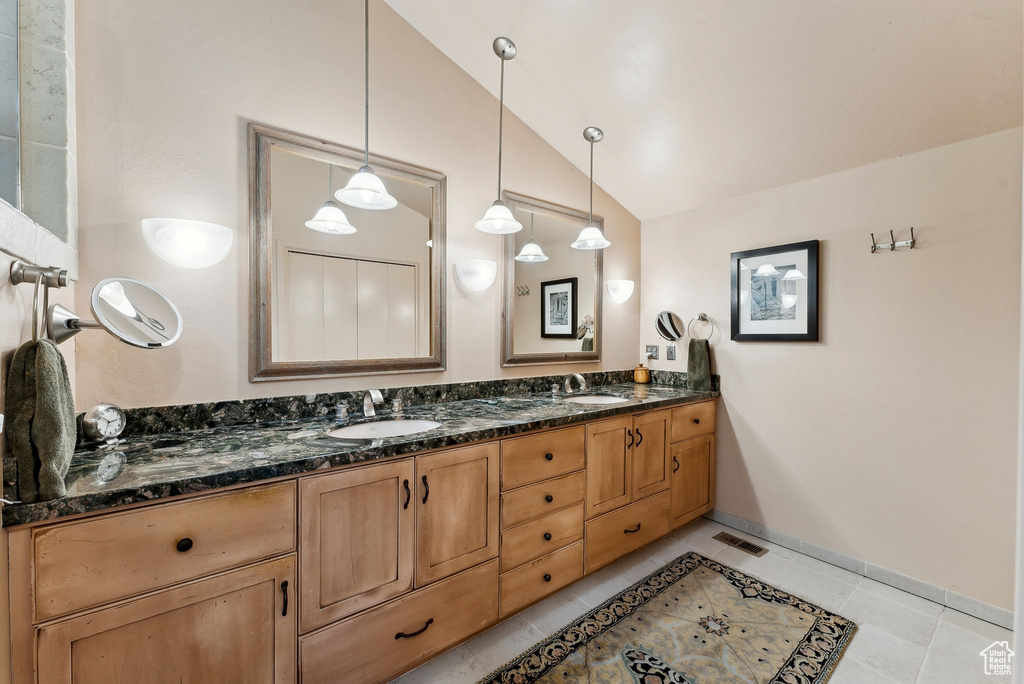 Full bathroom featuring lofted ceiling, double vanity, tile patterned floors, and baseboards