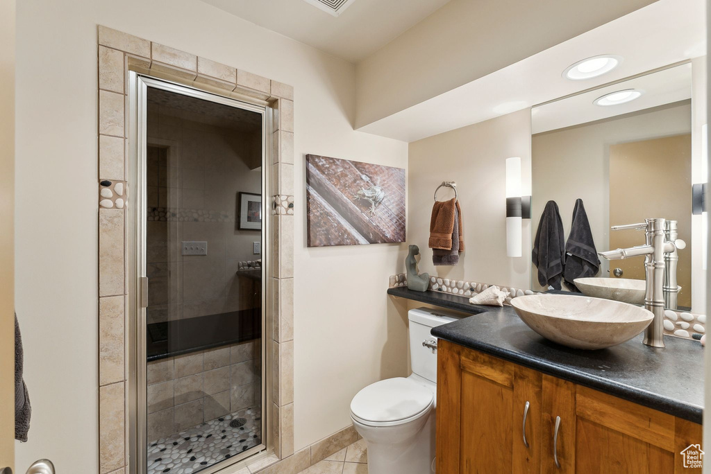 Bathroom featuring a stall shower, tile patterned flooring, vanity, and toilet