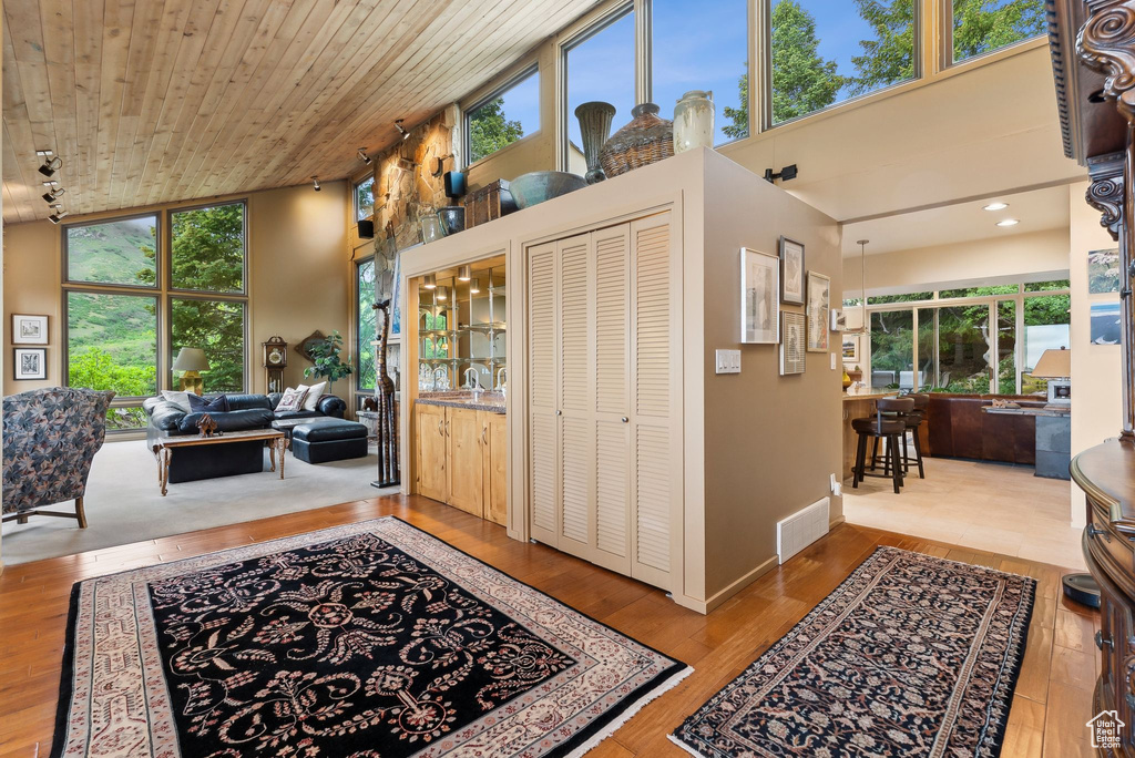 Foyer entrance featuring healthy amount of natural light, hardwood / wood-style floors, wooden ceiling, baseboards, and a high ceiling