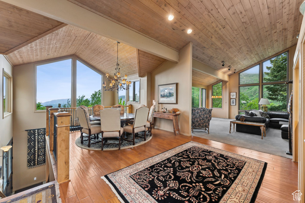 Dining room with vaulted ceiling, wood ceiling, hardwood / wood-style floors, and a chandelier
