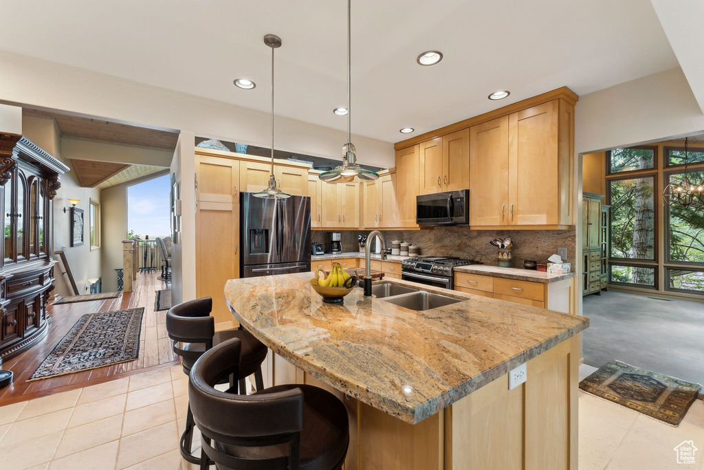 Kitchen featuring stainless steel appliances, backsplash, recessed lighting, light brown cabinets, and light stone counters