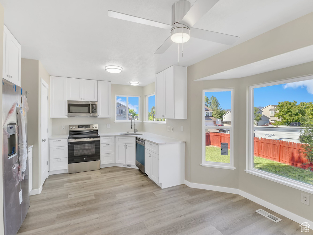 Kitchen with appliances with stainless steel finishes, light countertops, light wood-type flooring, and a sink