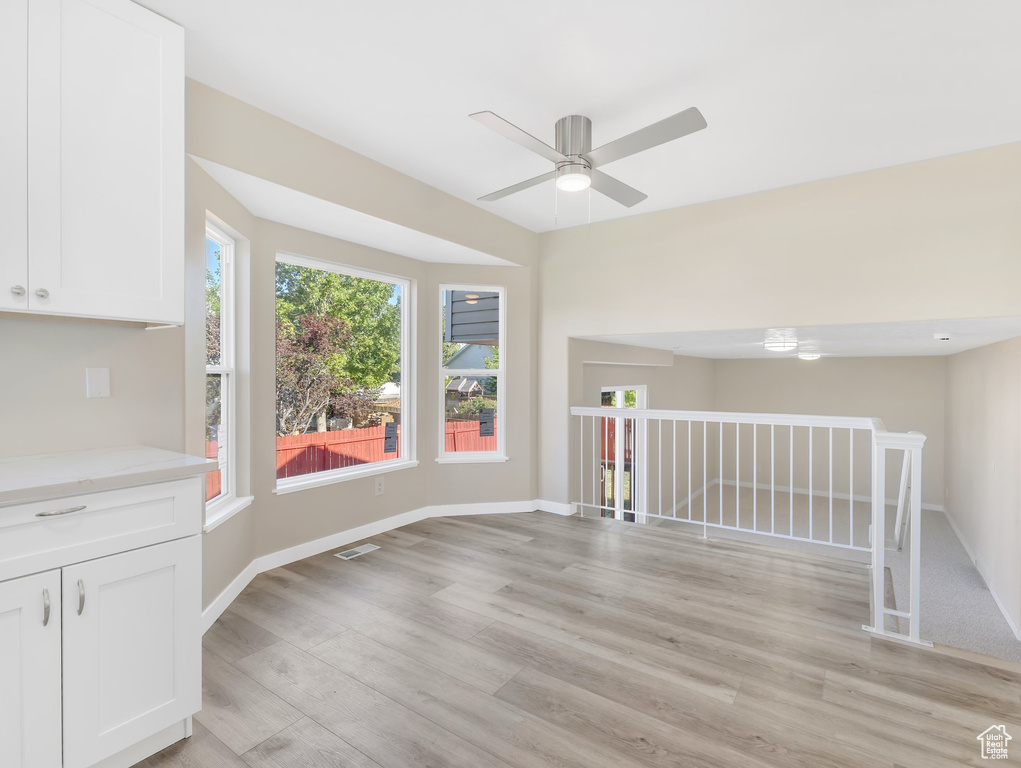 Unfurnished room featuring a ceiling fan, light wood-style floors, and baseboards