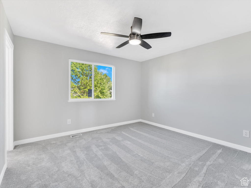 Carpeted empty room with a ceiling fan and baseboards