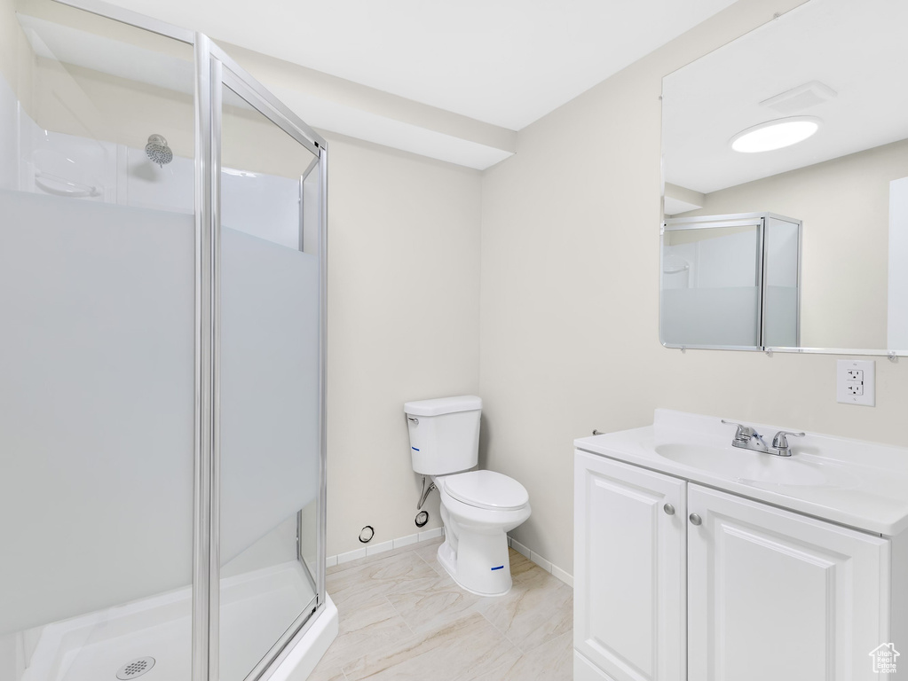 Full bath featuring a shower stall, toilet, vanity, marble finish floors, and baseboards