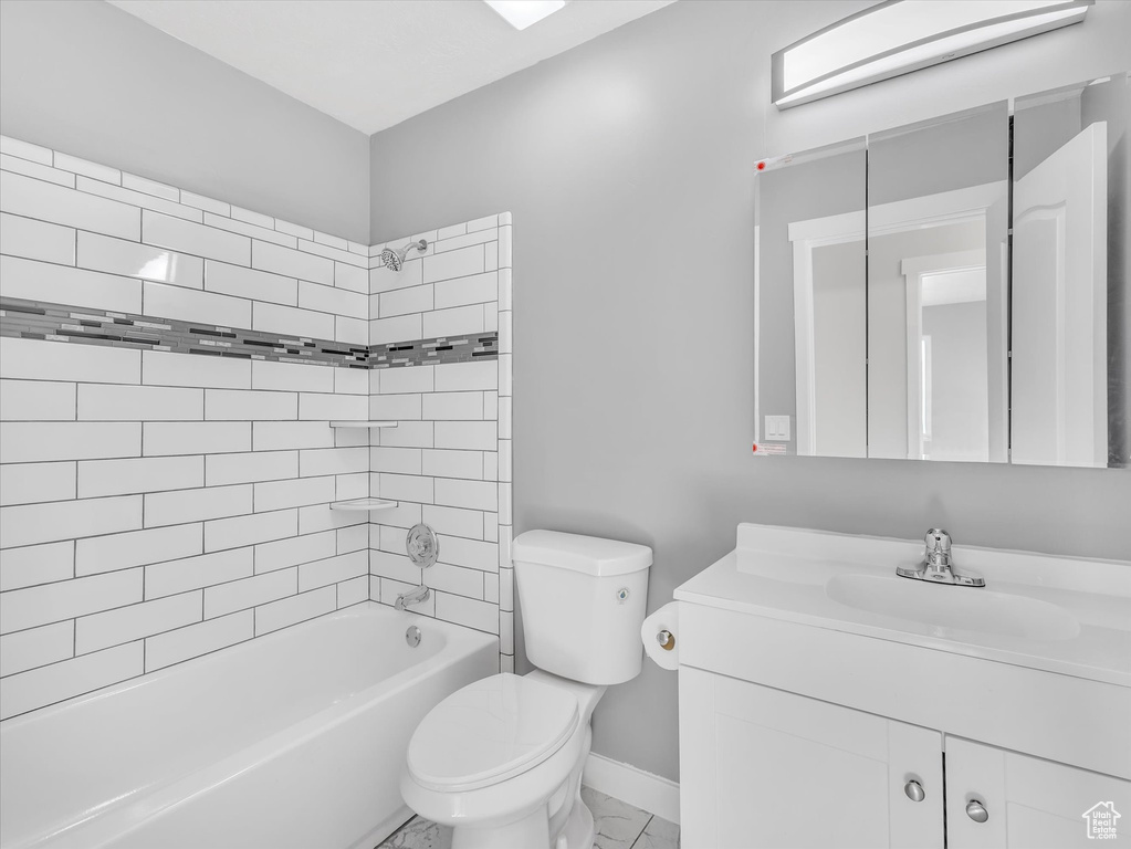 Bathroom with vanity, toilet, bathing tub / shower combination, marble finish flooring, and baseboards