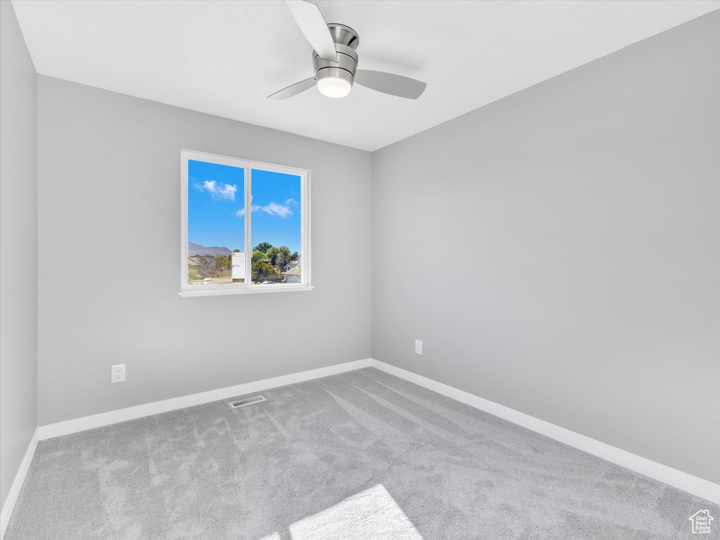 Carpeted empty room featuring a ceiling fan and baseboards