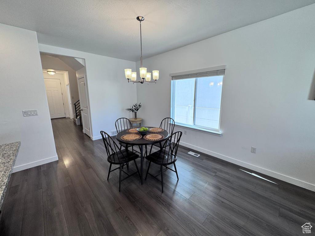 Dining area with dark wood-style flooring, a chandelier, and baseboards