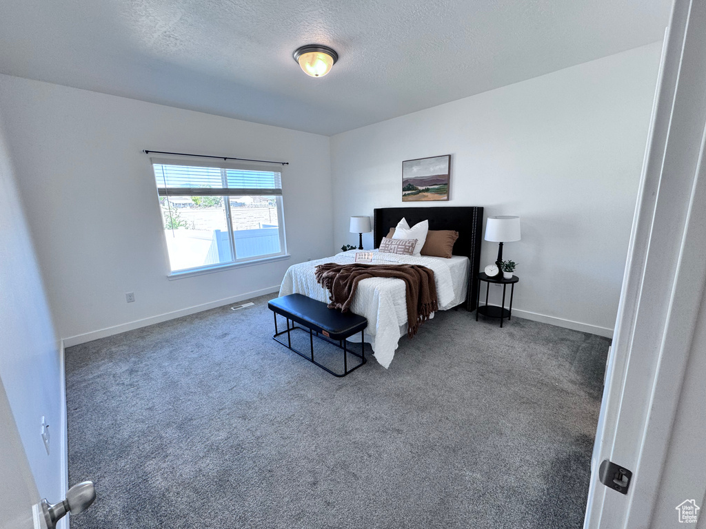 Carpeted bedroom featuring a textured ceiling and baseboards