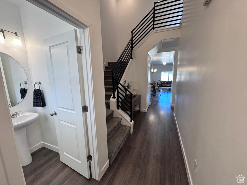 Corridor with dark wood-style flooring, stairway, baseboards, and arched walkways