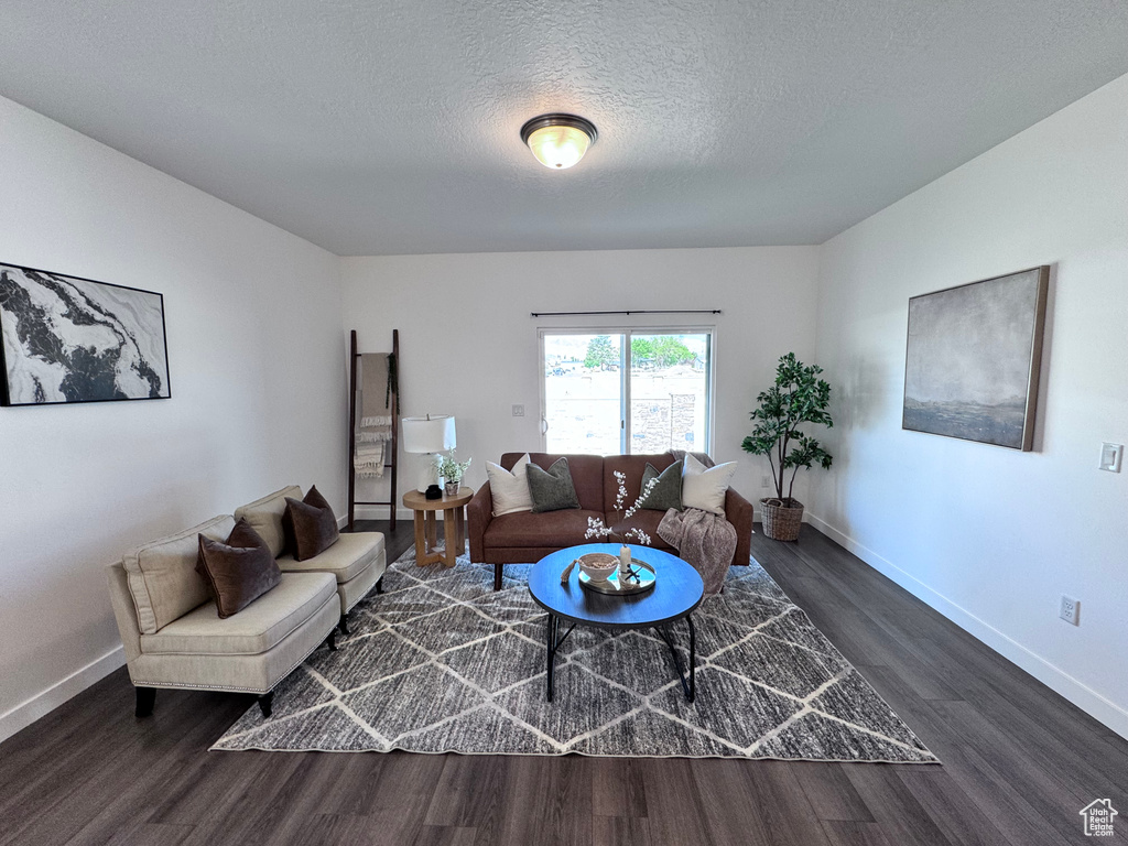 Living area with dark wood-style floors, baseboards, and a textured ceiling