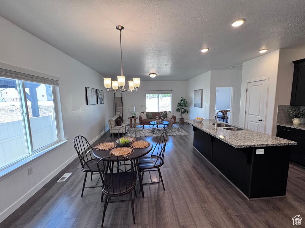 Dining room with dark wood finished floors, baseboards, a chandelier, a textured ceiling, and recessed lighting