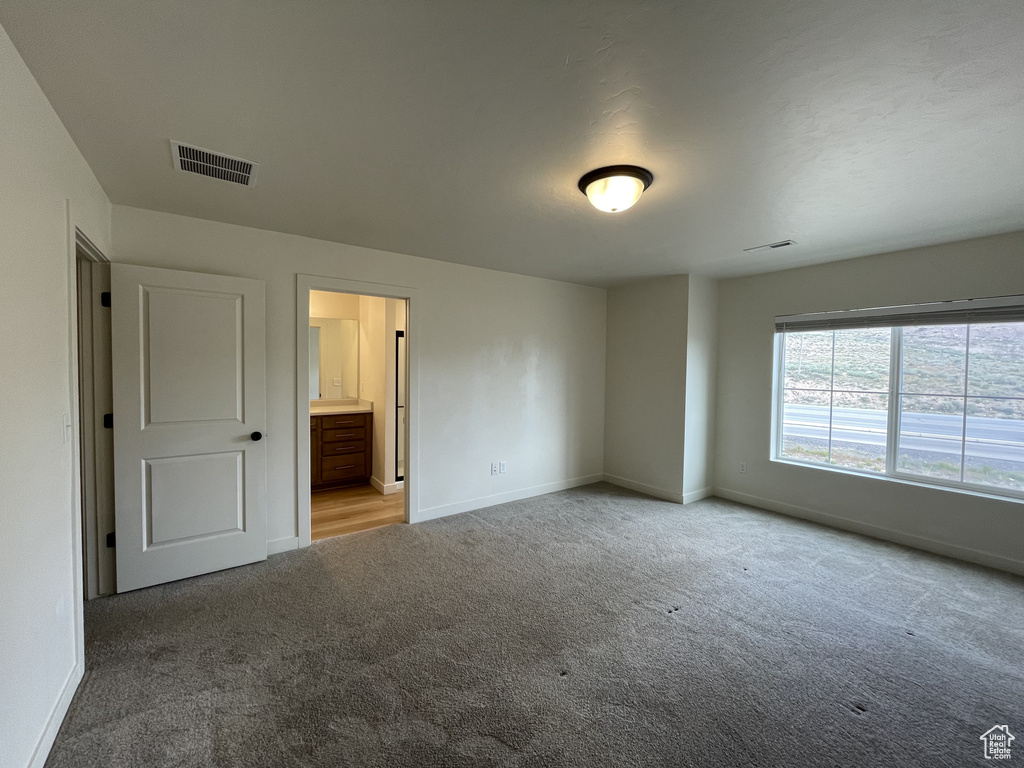 Unfurnished bedroom featuring carpet, baseboards, and ensuite bath