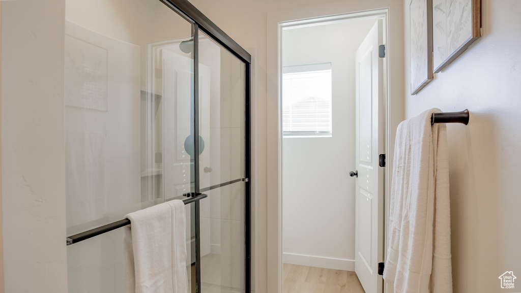 Full bathroom featuring wood finished floors, a shower stall, and baseboards