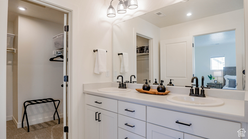 Bathroom with a spacious closet, double vanity, and baseboards