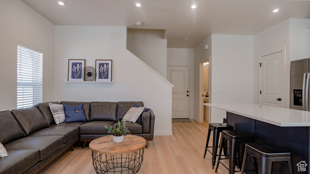 Living area featuring light wood finished floors, recessed lighting, baseboards, and stairs