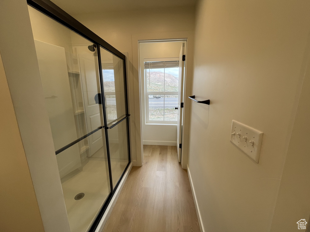 Full bath with wood finished floors, baseboards, and a shower stall