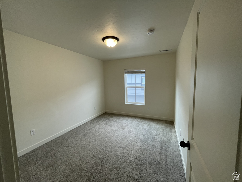 Carpeted spare room featuring baseboards and a smoke detector