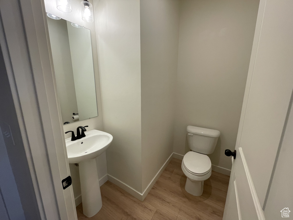 Bathroom featuring wood finished floors, toilet, a sink, and baseboards