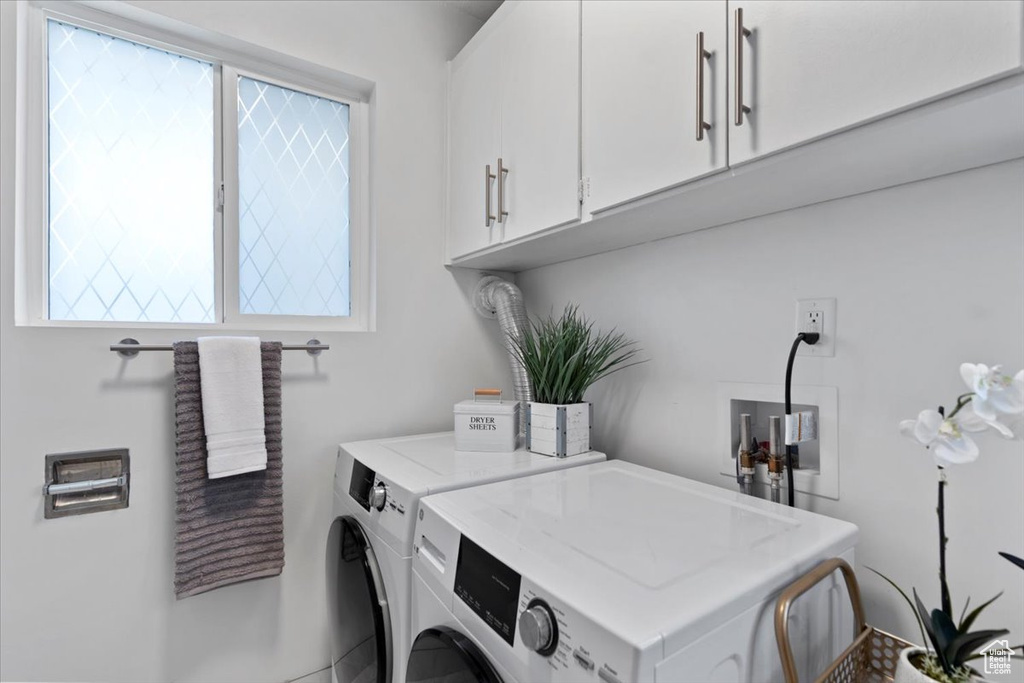 Washroom featuring washer and clothes dryer, healthy amount of natural light, and cabinet space
