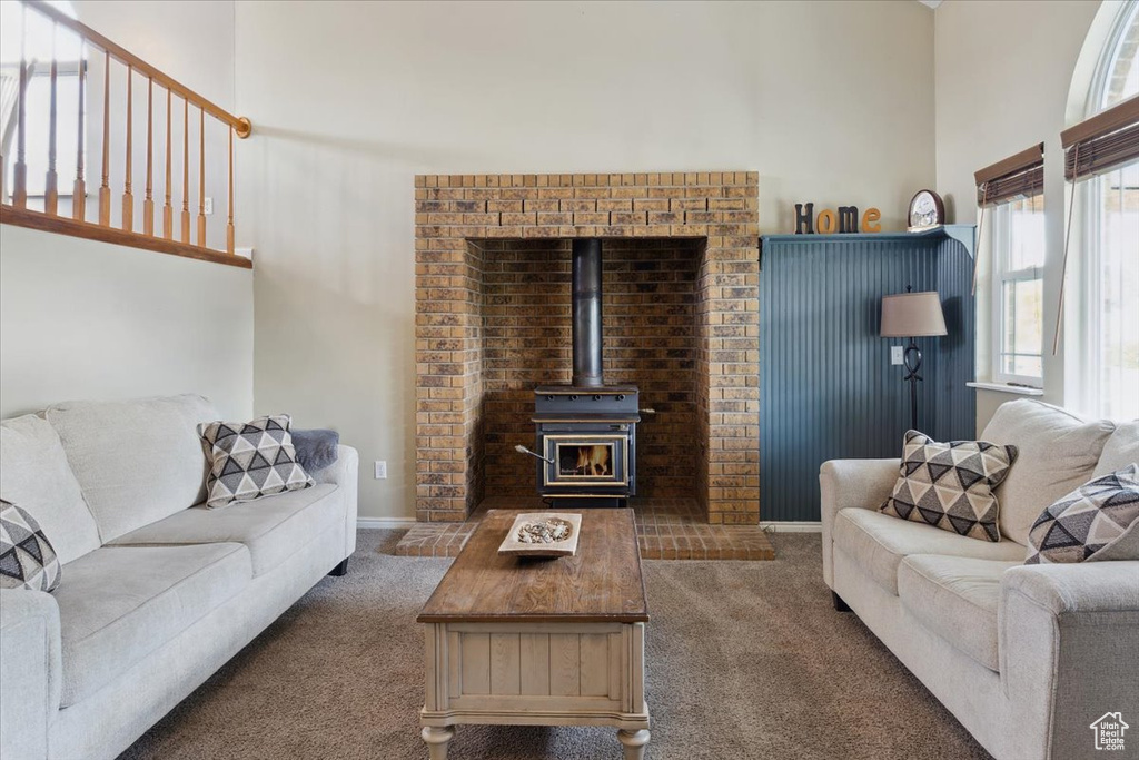 Carpeted living area featuring a towering ceiling and a wood stove