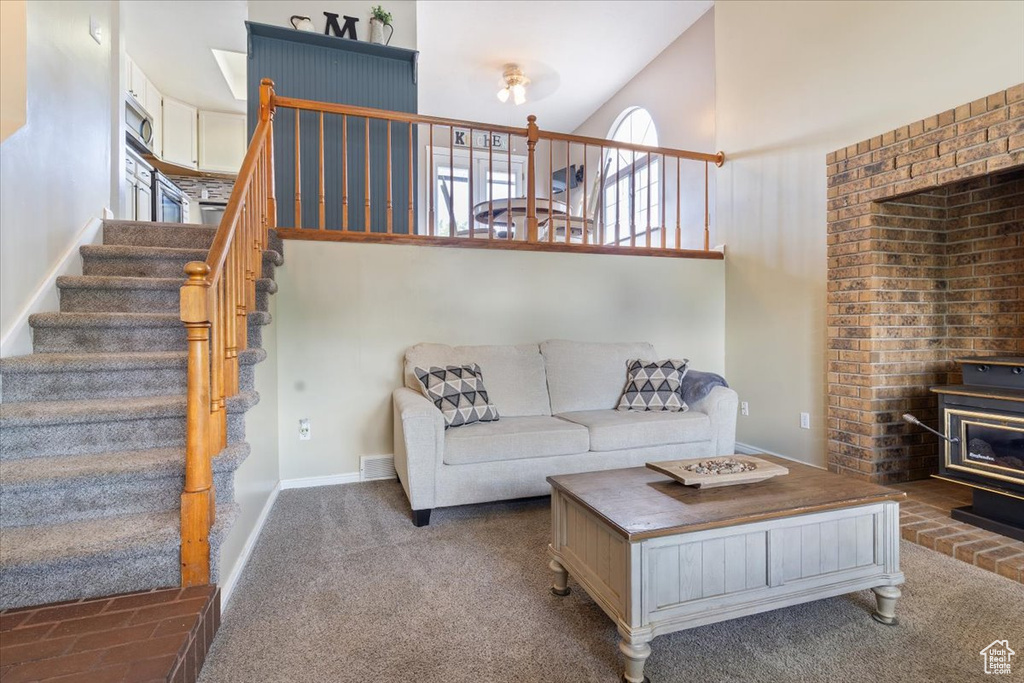Living area featuring a wood stove, stairs, a high ceiling, carpet flooring, and baseboards