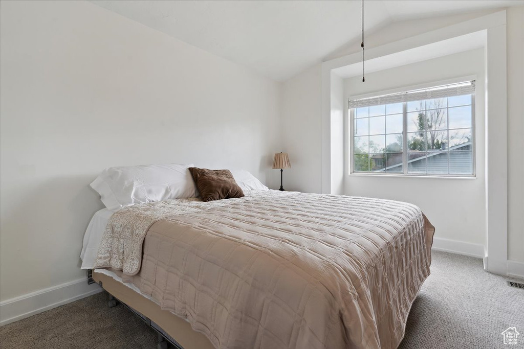 Carpeted bedroom with lofted ceiling and baseboards