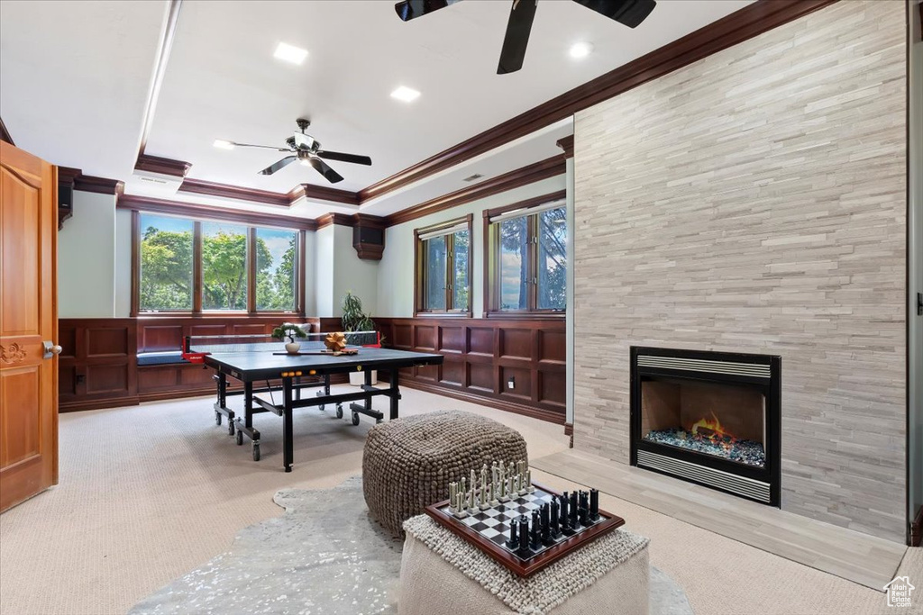 Dining area featuring ceiling fan, crown molding, a decorative wall, carpet, and a tiled fireplace