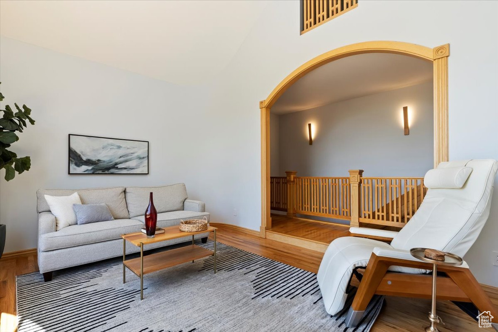 Living room featuring wood finished floors, arched walkways, baseboards, and a towering ceiling