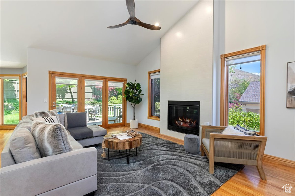 Living room featuring wood finished floors, high vaulted ceiling, french doors, ceiling fan, and a large fireplace
