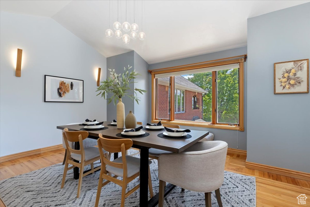 Dining area with baseboards, lofted ceiling, and light wood-style flooring