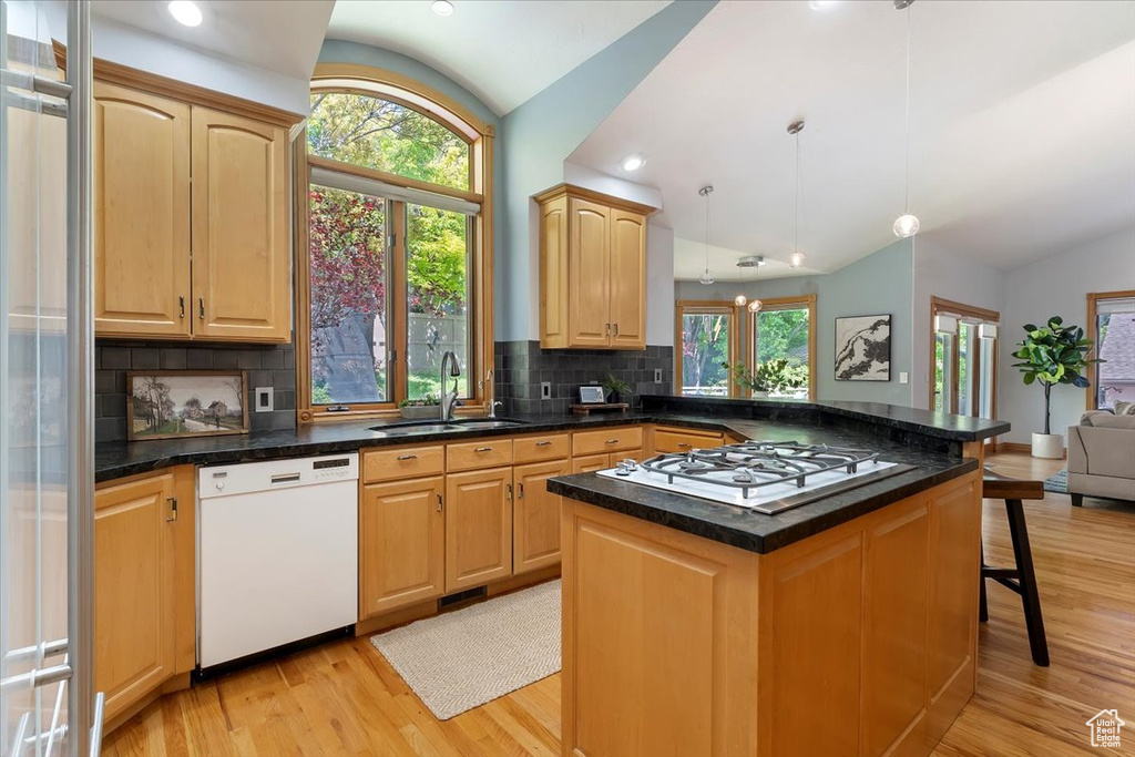 Kitchen with white dishwasher, vaulted ceiling, a sink, stainless steel gas stovetop, and light wood finished floors