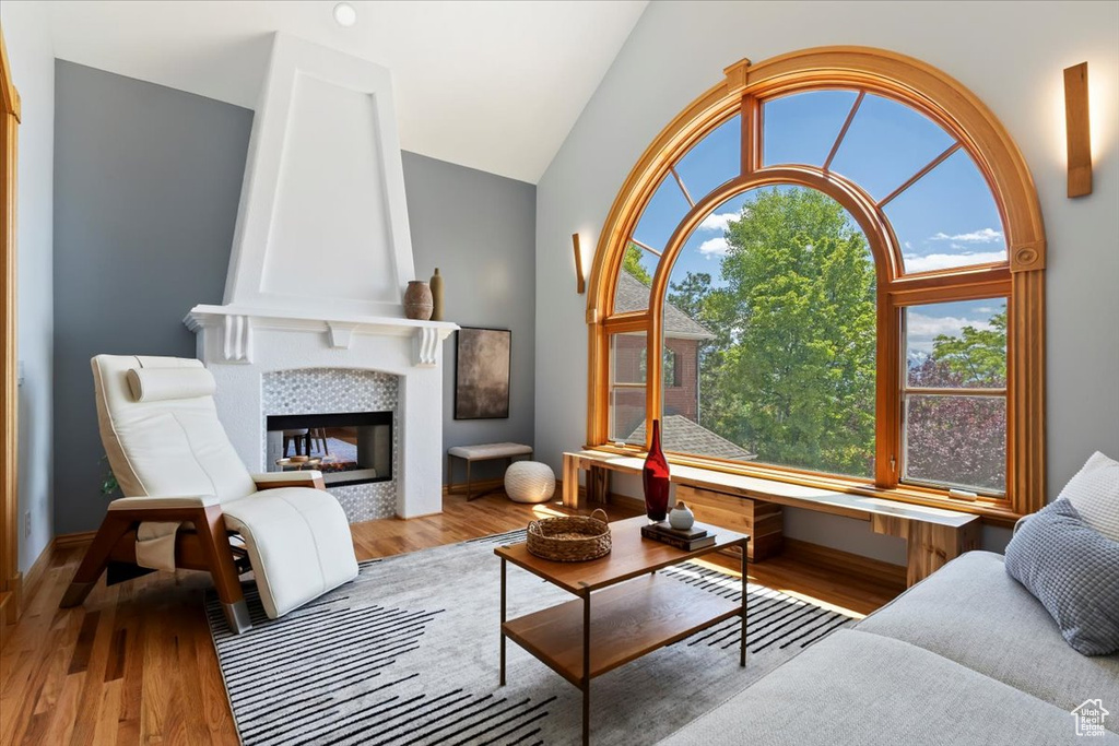 Living area featuring vaulted ceiling, wood finished floors, and a tiled fireplace