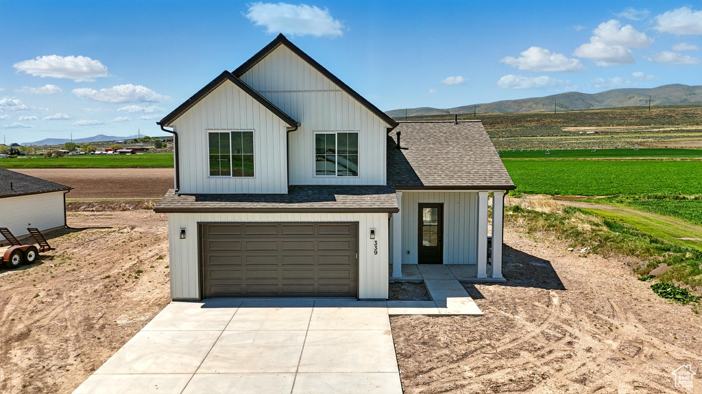 Modern farmhouse featuring a mountain view, driveway, a garage, and a shingled roof