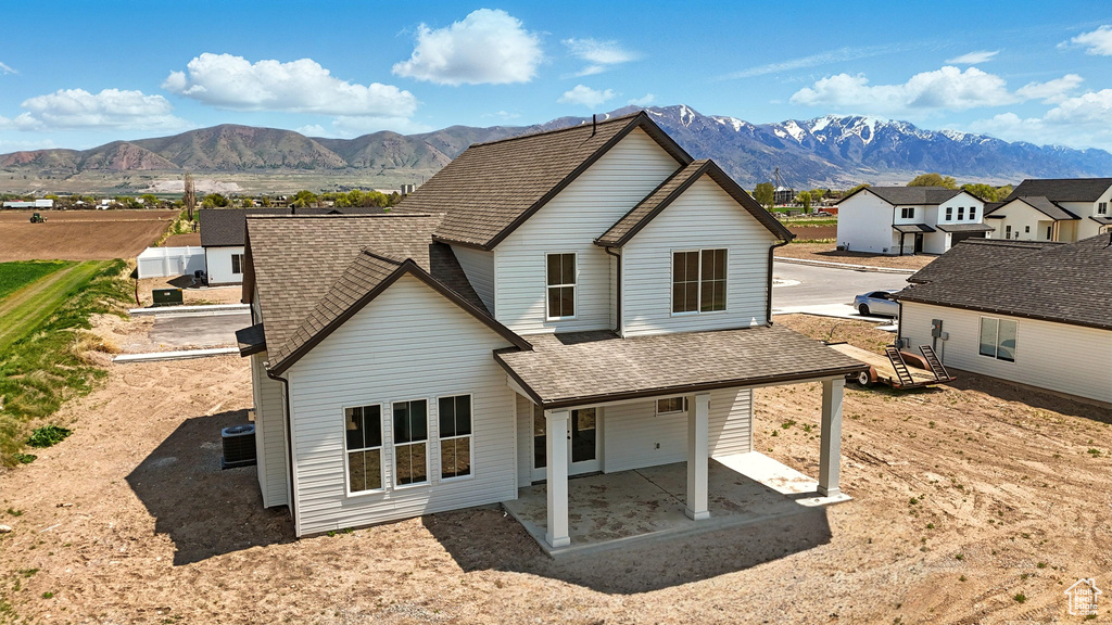 Rear view of property with a mountain view, a shingled roof, and a residential view