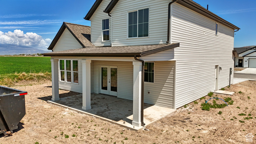 Rear view of house featuring french doors, a patio, and roof with shingles