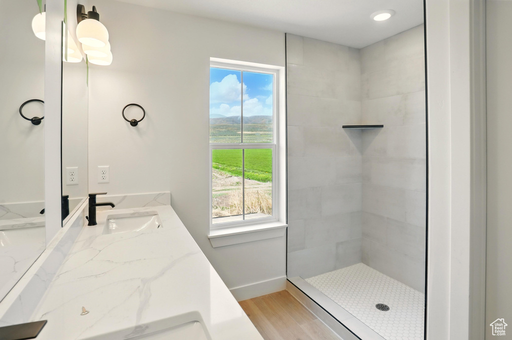 Full bathroom featuring vanity, plenty of natural light, baseboards, and tiled shower