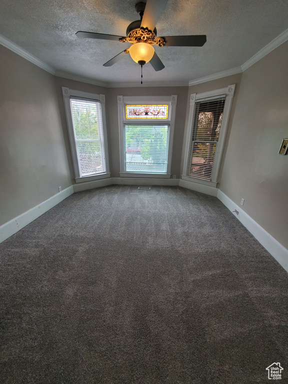 Empty room featuring a textured ceiling, carpet floors, crown molding, baseboards, and a ceiling fan