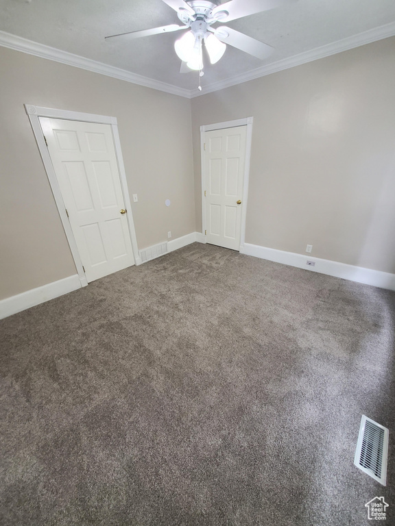 Unfurnished bedroom featuring crown molding, baseboards, dark carpet, and ceiling fan