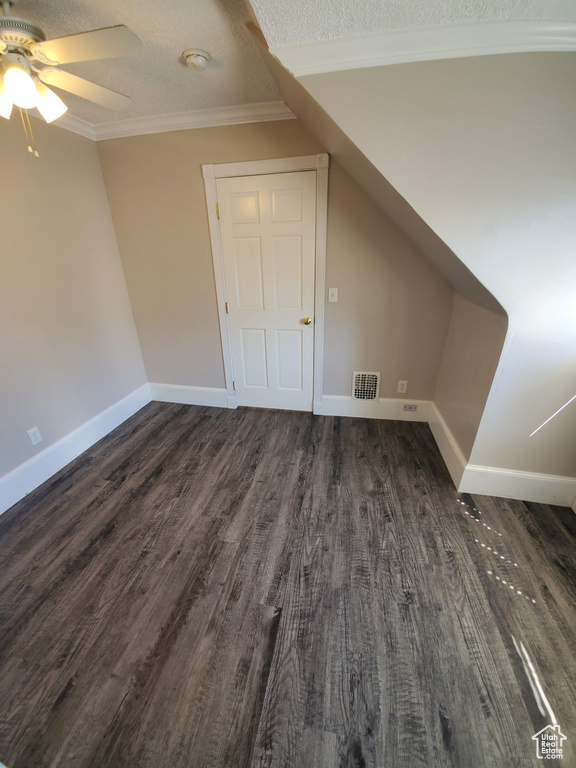 Additional living space featuring dark wood-style floors, ceiling fan, baseboards, and a textured ceiling